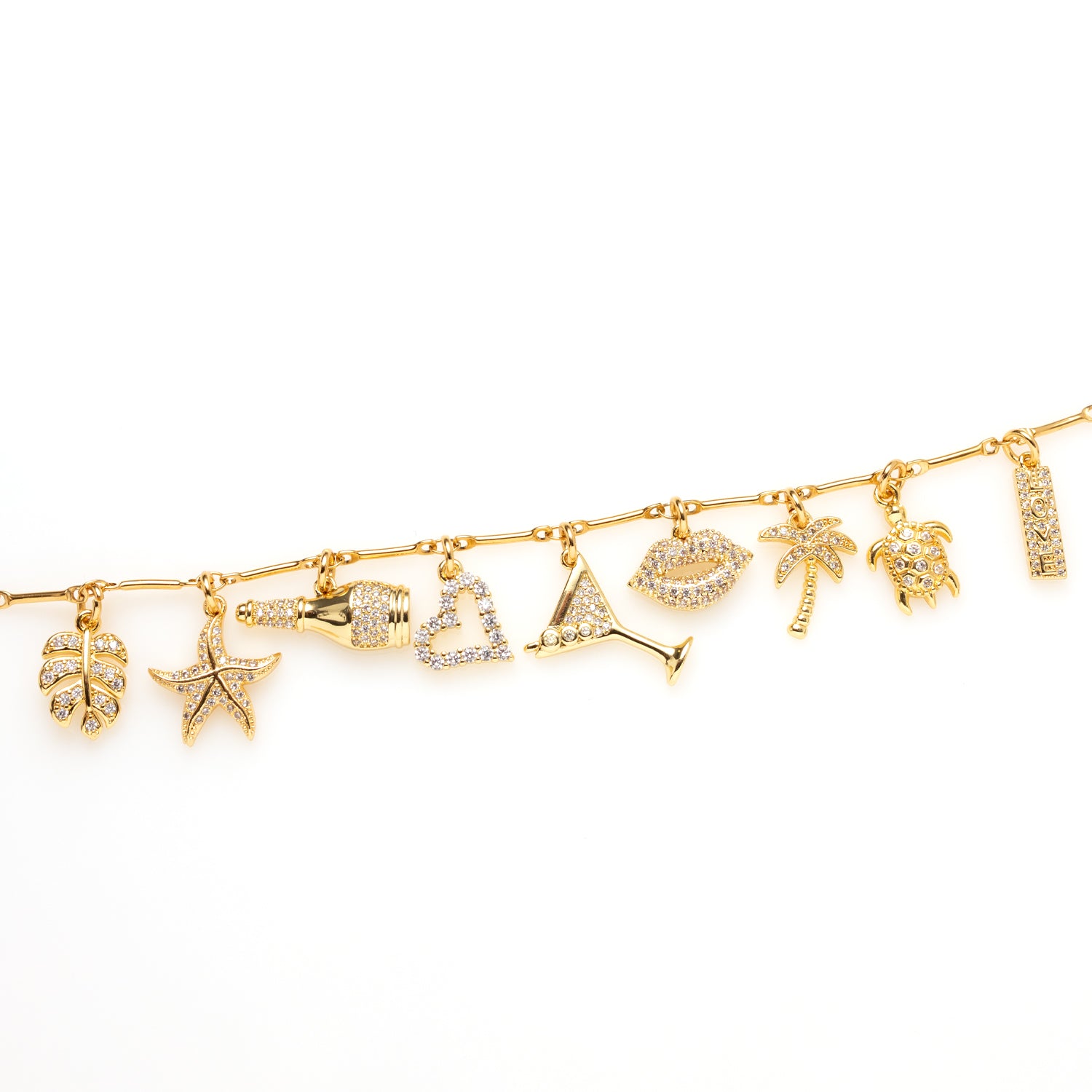 Bedelarmband goud, rvs stainless steel, 15 cm. De armband is rijkelijk versierd met sprankelende zirkonia bedels in de vorm van een palmblad, zeester, champagnefles, hartje, cocktailglas, lipjes, palmboom, schildpad én het woordje love. Elke bedel vertelt een verhaal – van zwoele strandkussen tot bruisende zomeravonden met een glas bubbels in je hand.