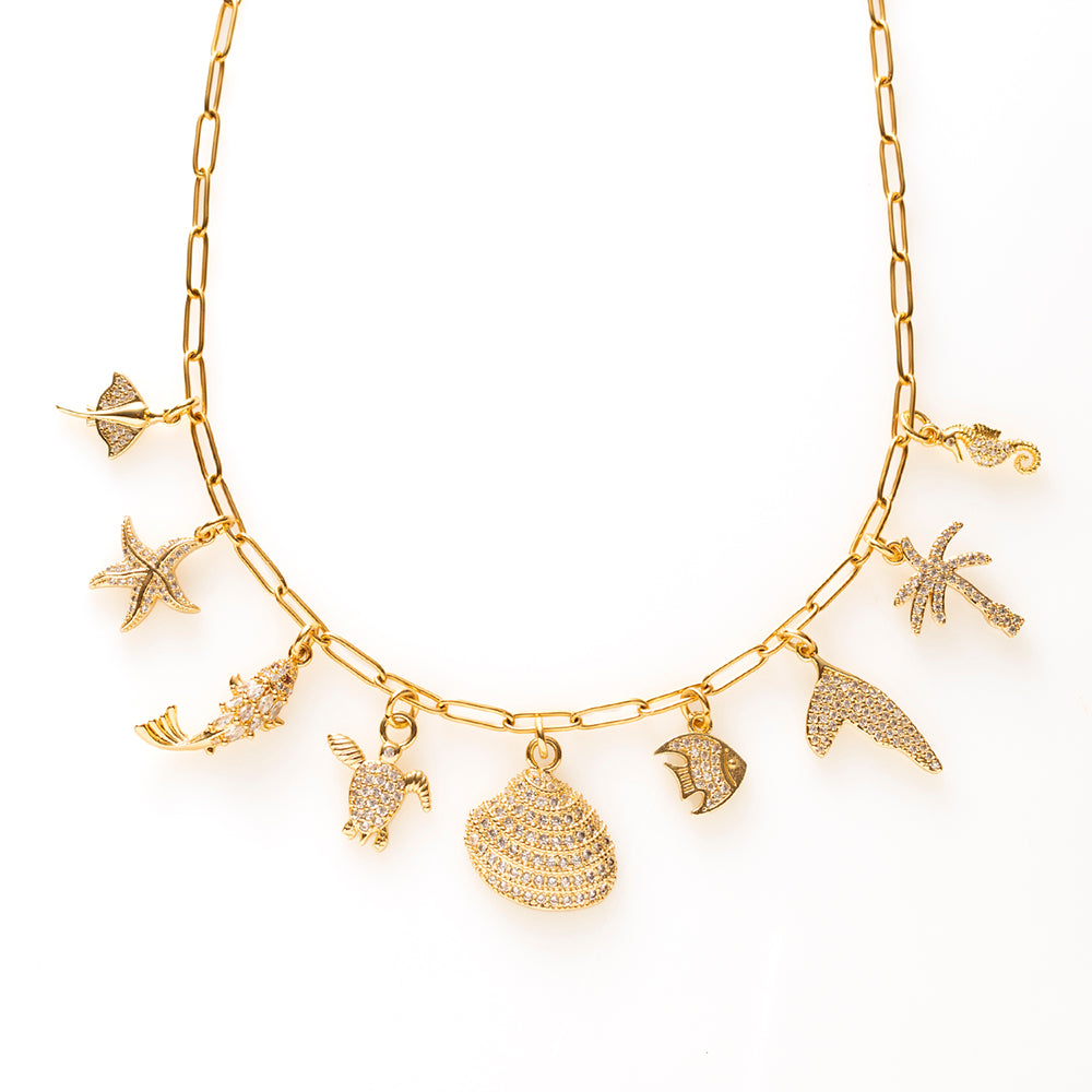 Breng de zon, zee en het strand altijd met je mee met Ocean Glow. Deze verfijnde gouden bedelketting is een ode aan de oceaan, met speelse bedels zoals een schildpad, zeepaardje, palmboom, schelp en andere zomerse bedels. De sprankelende zirkonia steentjes geven de ketting een elegante, luxe finishing touch.
Een vrolijke statement ketting die moeiteloos past bij zowel een luchtige zomerjurk als een casual outfit.