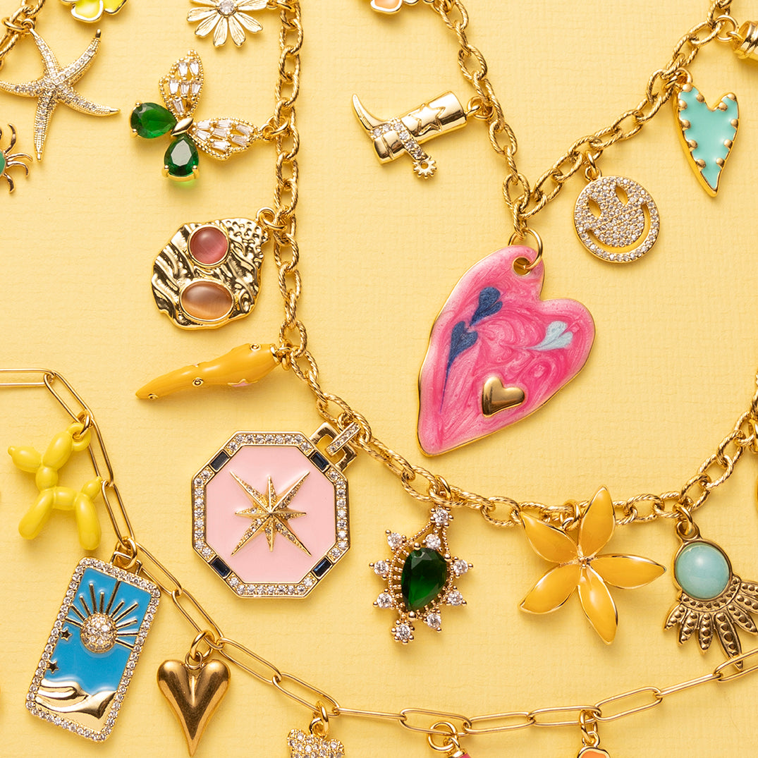 Bedelketting met verschillende gekleurde bedels. Een groot roze hart, koffiebeker, cowboylaars, zirkonia smiley, turquoise hartje, blauwe peper, oranje hartje, roze hartje klein.