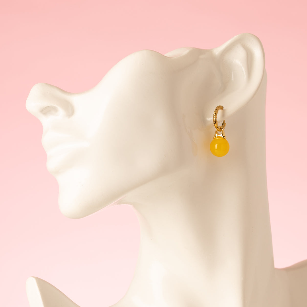Geef je look een warme, zonnige touch met de Golden Hour oorbellen. Aan een goudkleurige klapcreool met fijne gehamerde structuur hangt een glanzend bolletje geel agaat, dat het licht vangt bij iedere beweging. Klein van formaat en rijk van kleur. Subtiel genoeg voor elke dag, opvallend genoeg voor een zomerse jurk of een witte blouse op kantoor.