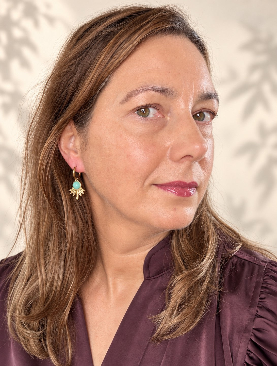 Geef je look een frisse, natuurlijke uitstraling met de Aqua Bloom oorbellen. Aan een fijne gouden klapcreool hangt een bewerkte waaier van gouden blaadjes, gekroond door een ronde amazoniet in zacht blauw. De open vorm vangt het licht en geeft de oorbellen een opvallend silhouet, terwijl het lichte gewicht ze de hele dag comfortabel houdt. Elegant genoeg voor een speciale gelegenheid, maar ook ideaal voor elke dag.