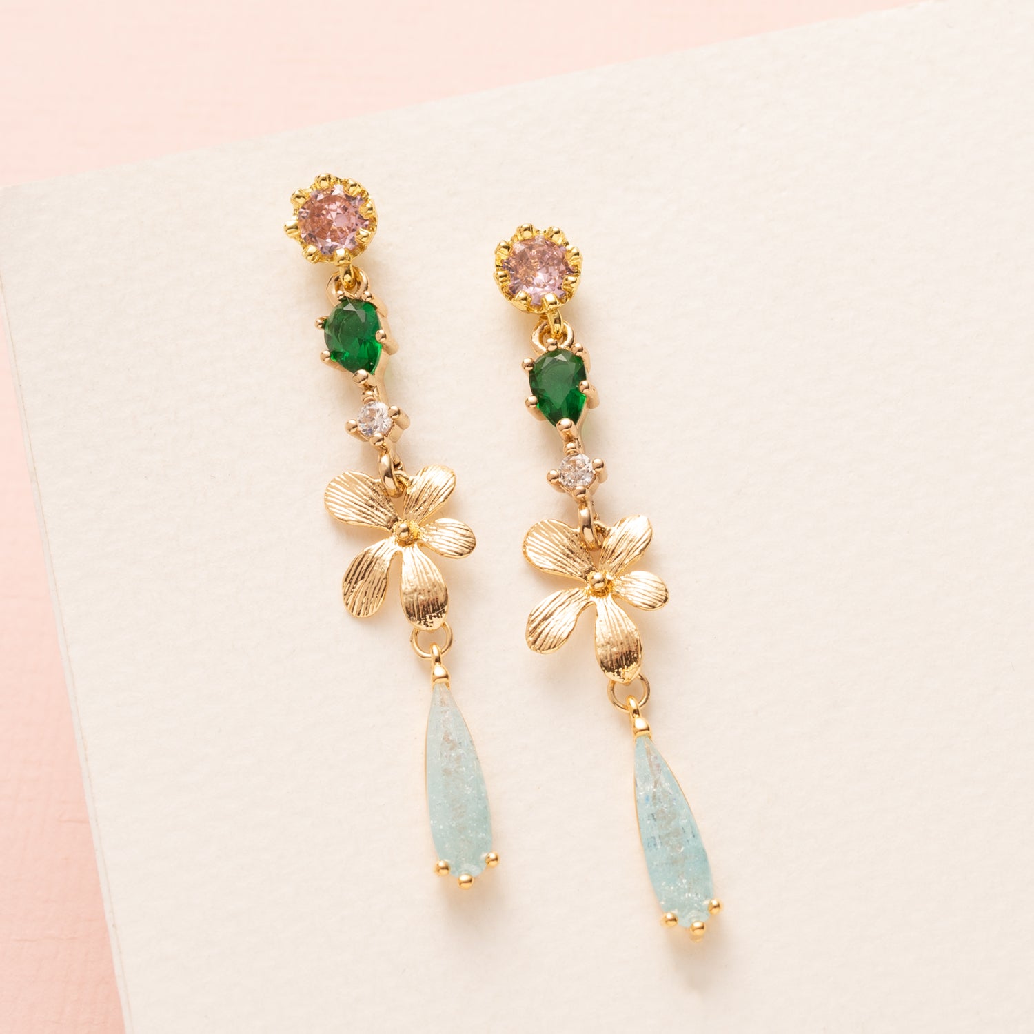Breng een verfijnde herfstachtige elegantie in je look met de Whispering Grove oorbellen. Lichtroze zirkonia oorstekers vormen een zacht begin, gecombineerd met een frisgroen zirkonia tussenstuk daar onder een gouden bloem. Subtiele lichtblauwe zirkonia druppels geven een sprankelend accent en maken deze oorbellen perfect voor het najaar, naar kantoor of een etentje. Elegant, stijlvol en tijdloos en een gedurfde kleurcombinatie.