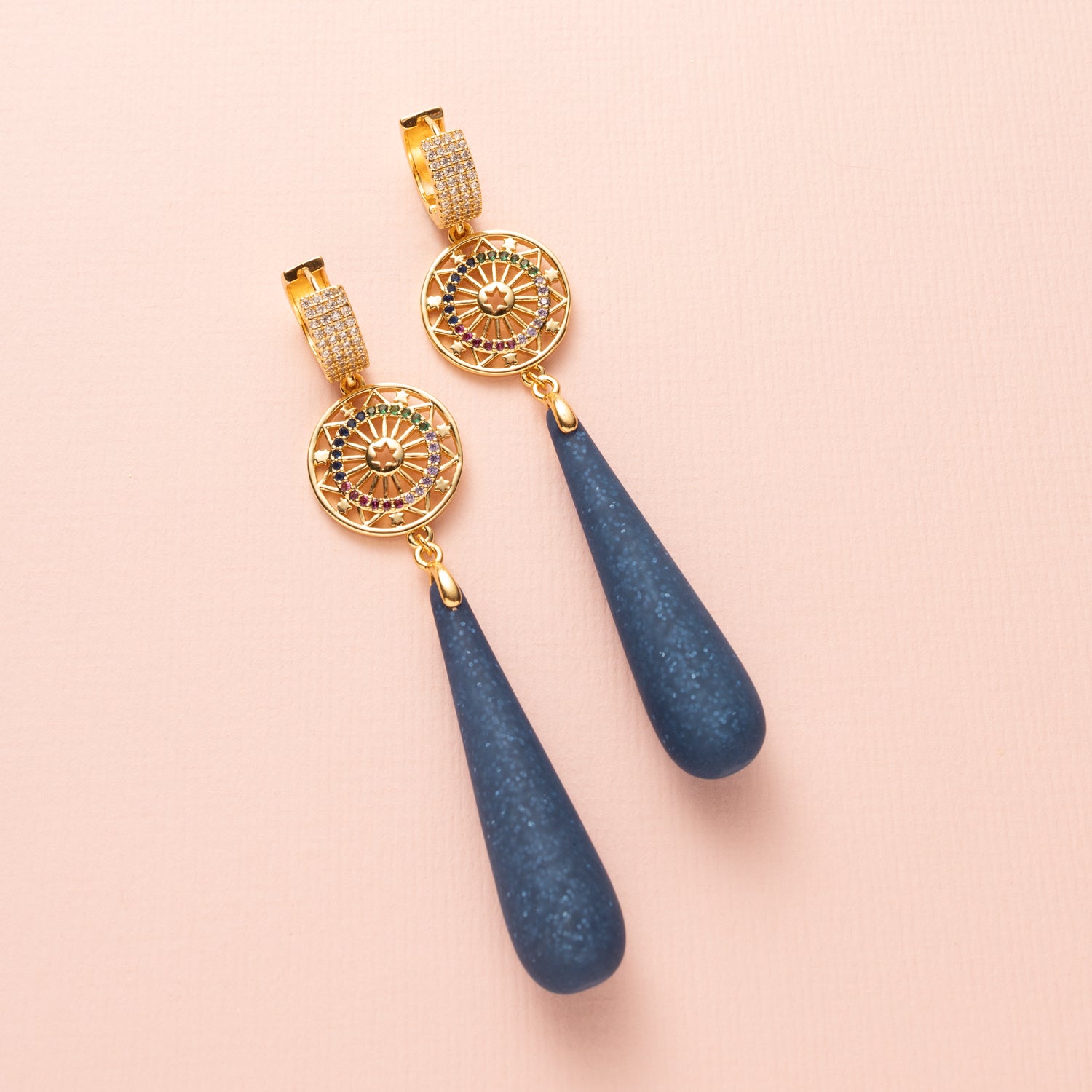 Celestial Blue is een oogstrelende oorbel die glamour en kleur samenbrengt. De zirkonia oorringen verbinden zich met een rond tussenstuk, versierd met fonkelende zirkonia steentjes in verschillende kleuren. Daaronder hangen matte Polaris druppels in royal blue met subtiele glitters, die elke beweging een sprankelende, bijna magische touch geven.
Een perfecte oorbel voor vrouwen die durven te stralen met elegantie en kleur, van dag tot avond.