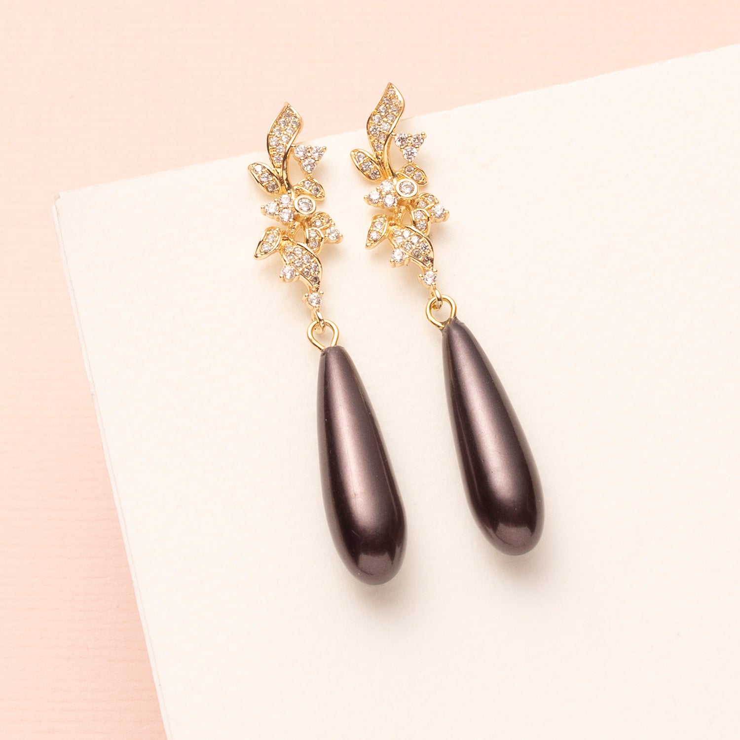 Midnight Muse straalt stille luxe uit. De oorstekers zijn verfijnd vormgegeven met sierlijke zirkonia blaadjes die licht vangen bij elke beweging.
Onder deze elegante top schittert een Japanse pareldruppel in de diepe, mysterieuze kleur graphite, een perfecte balans tussen modern chic en tijdloze elegantie.
Een subtiel statement voor vrouwen die hun stijl moeiteloos laten spreken, zowel op kantoor als tijdens een avondje uit.