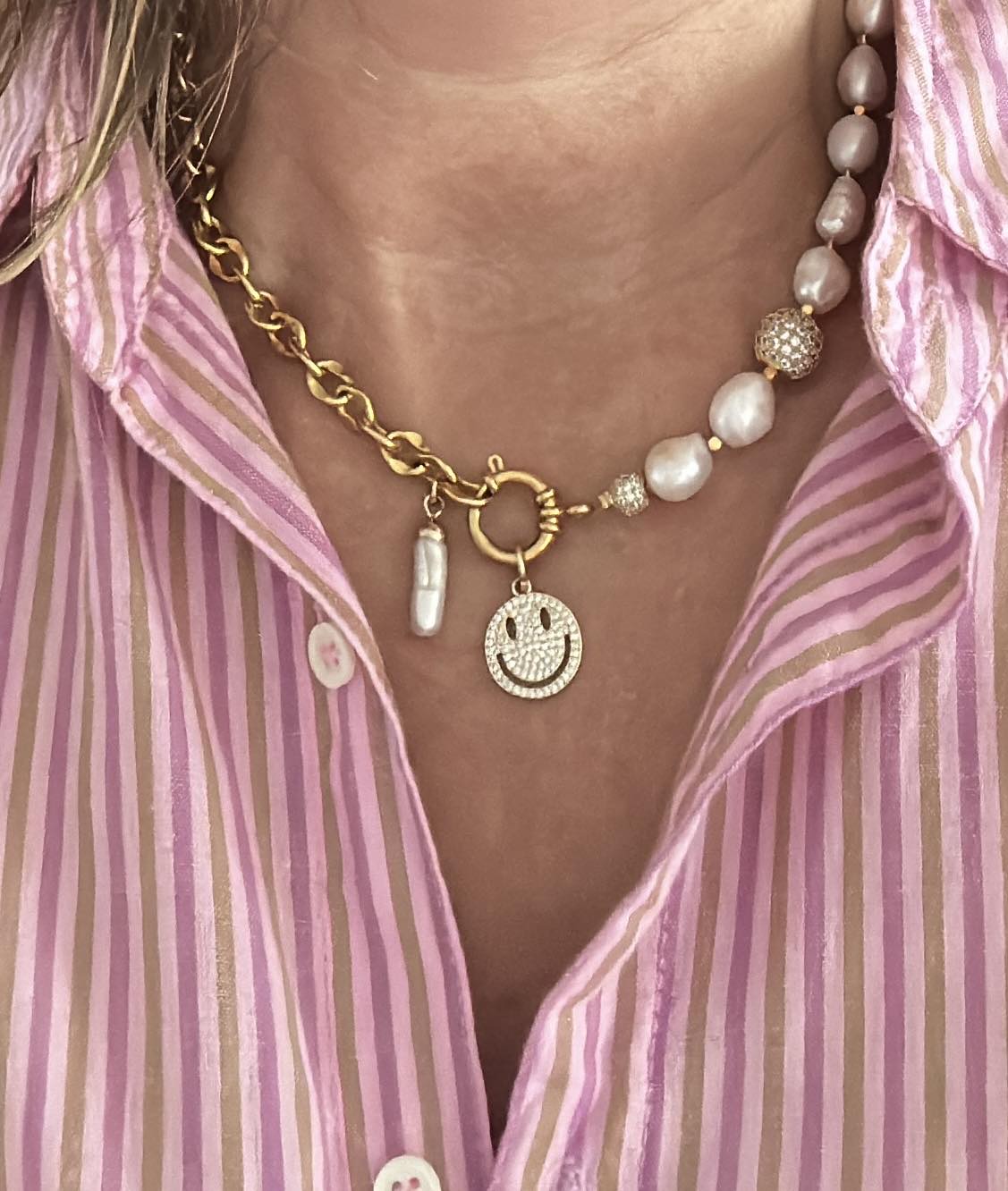 Deze moderne parelketting combineert het beste van twee werelden: de zachte elegantie van zoetwaterparels en de krachtige uitstraling van een opvallende schakel. Aan de voorkant zit een stijlvol boeislot met een zirkonia smiley die je eenvoudig kunt verwijderen. Zo wissel je moeiteloos tussen speels en puur. Een trendy maar tijdloos ontwerp dat zowel stoer als chique gedragen kan worden, passend bij elke stijl en gelegenheid.