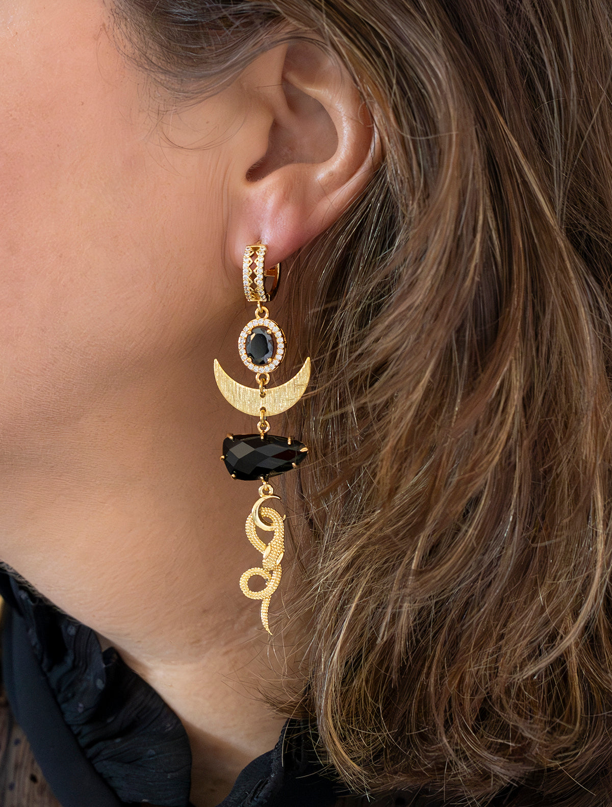 Deze asymmetrische statement oorbellen combineren mysterie en luxe in een gedurfd ontwerp. Met diepzwarte stenen die het licht op subtiele wijze vangen, en een sierlijke slang – het ultieme symbool van transformatie en kracht. De combinatie van stoer en elegant maakt deze oorbellen perfect voor vrouwen die durven opvallen. Een edgy eye-catcher die elke look naar een hoger niveau tilt! 