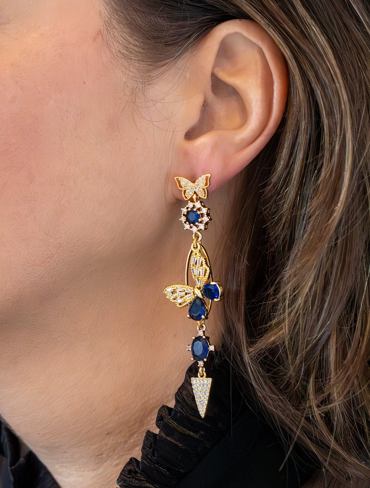 Asymmetrische Statement Oorbellen met zirkonia vlinder oorstekers, aan de linker oorbel een grote zirkonia vlinder met donkerblauw aan de rechter oorbel een kleinere donker blauwe zirkonia vlinder.