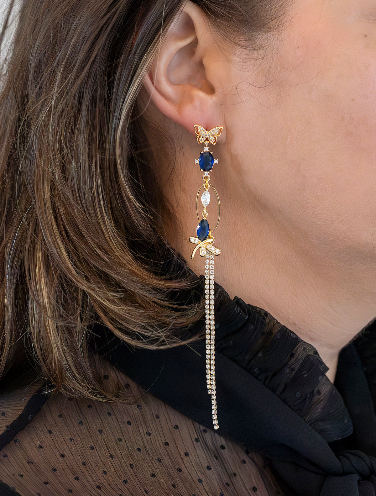 Asymmetrische Statement Oorbellen met zirkonia vlinder oorstekers, aan de linker oorbel een grote zirkonia vlinder met donkerblauw aan de rechter oorbel een kleinere donker blauwe zirkonia vlinder.