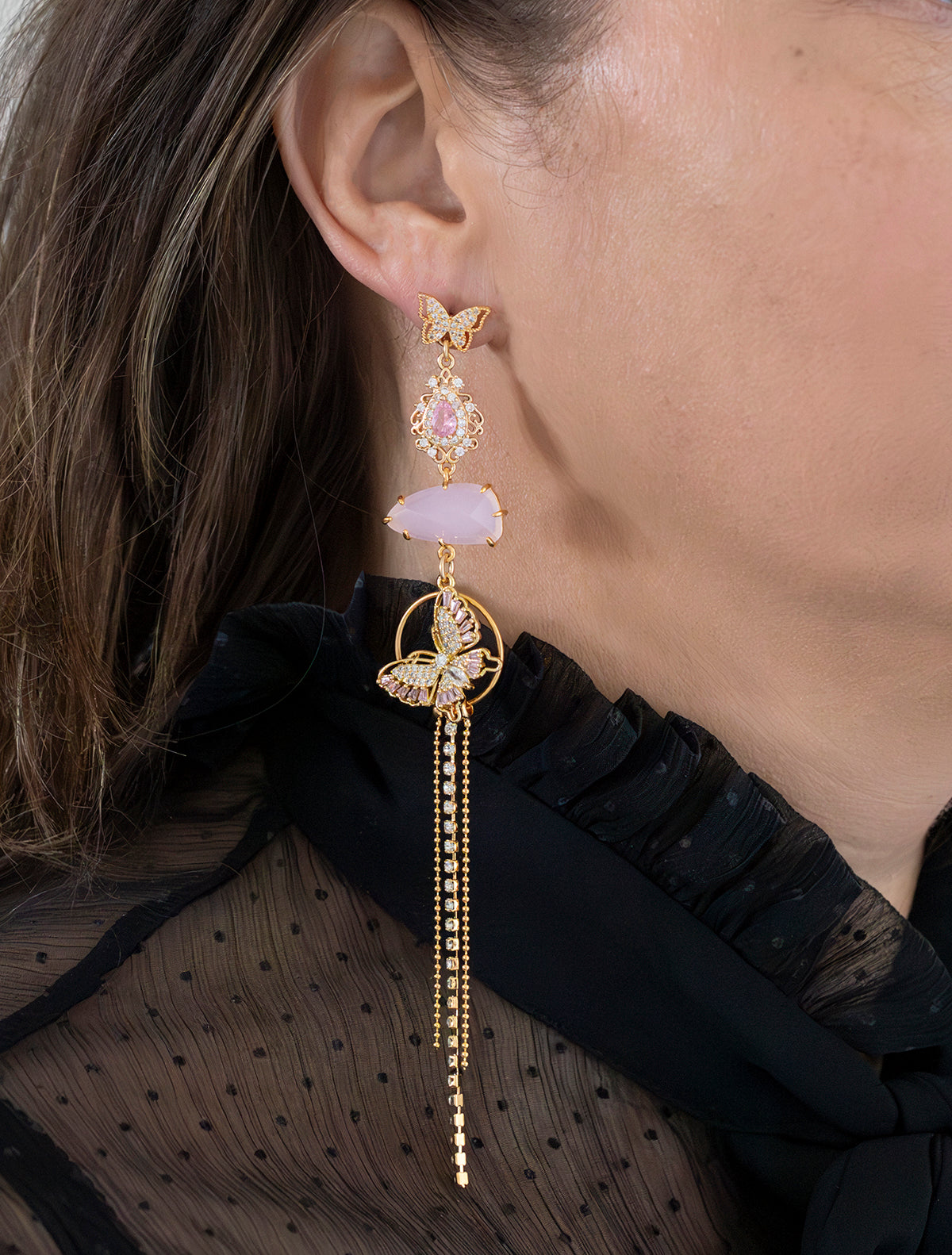 Asymmetrische statement oorbellen met zirkonia vlinder oorstekers. Een mix van glanzende en mat roze stenen en een roze vlinder