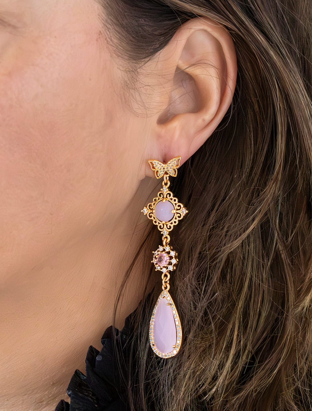 Asymmetrische statement oorbellen met zirkonia vlinder oorstekers. Een mix van glanzende en mat roze stenen en een roze vlinder