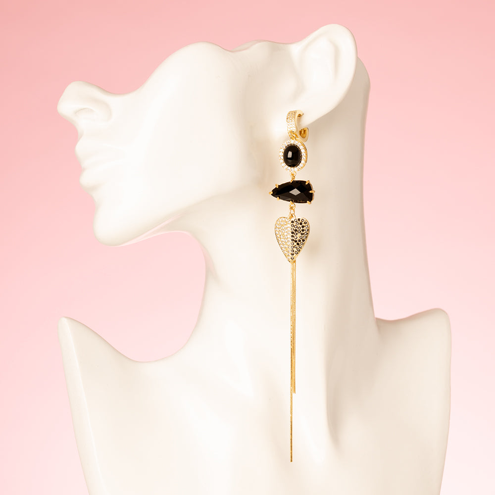 Asymmetrische Statement Oorbellen met zirkonia oorringen in goud. Zwarte stenen en een zirkonia hart en zwart en kristal. Grote en opvallende oorbellen