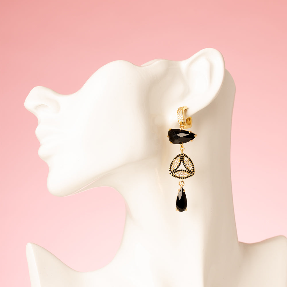 Asymmetrische Statement Oorbellen met zirkonia oorringen in goud. Zwarte stenen en een zirkonia hart en zwart en kristal. Grote en opvallende oorbellen