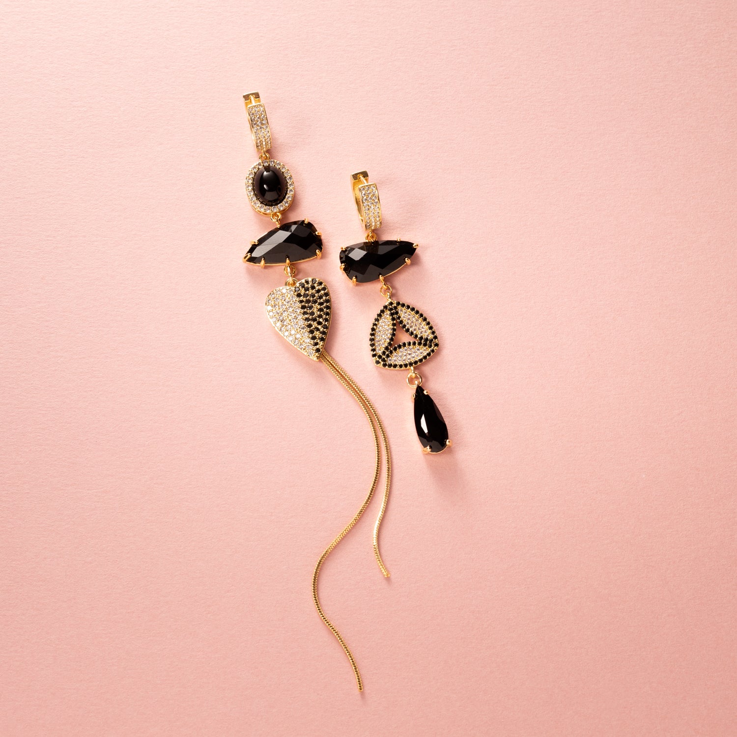 Asymmetrische Statement Oorbellen met zirkonia oorringen in goud. Zwarte stenen en een zirkonia hart en zwart en kristal. Grote en opvallende oorbellen