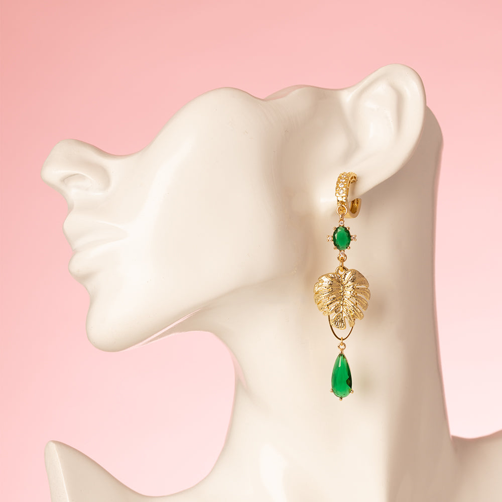 Asymmetrische statement oorbellen met een papegaai en een monstera blad. Met zirkonia oorringen en zirkonia bedels in de kleuren goud en groen