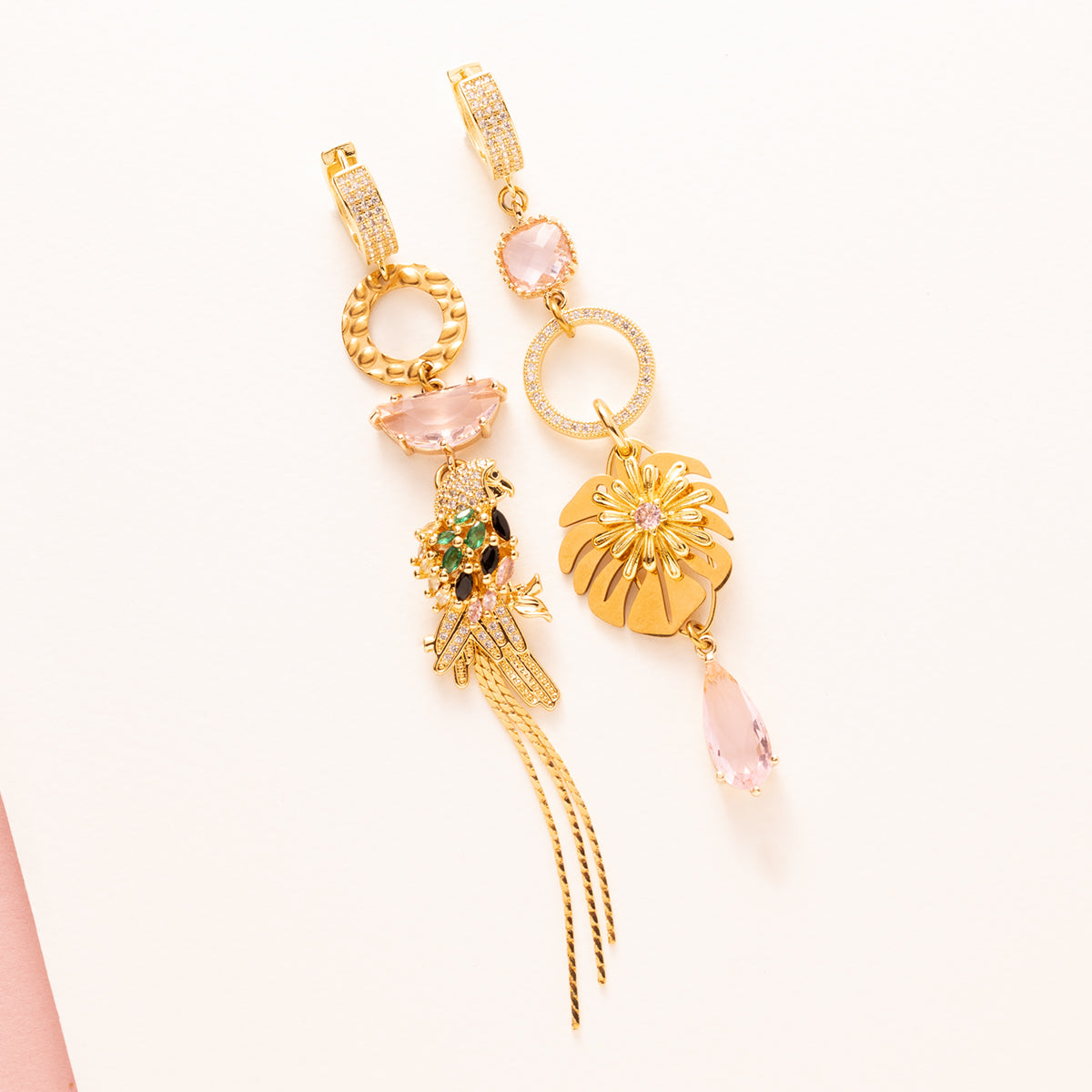 Voeg een vleugje fun & flair toe aan je look met deze asymmetrische statement oorbellen. Een speelse papegaai met sprankelende roze stenen siert de ene kant, terwijl een sierlijk palmblad de andere kant compleet maakt. Lief, vrolijk en tropisch – perfect voor een frisse en opvallende uitstraling! 