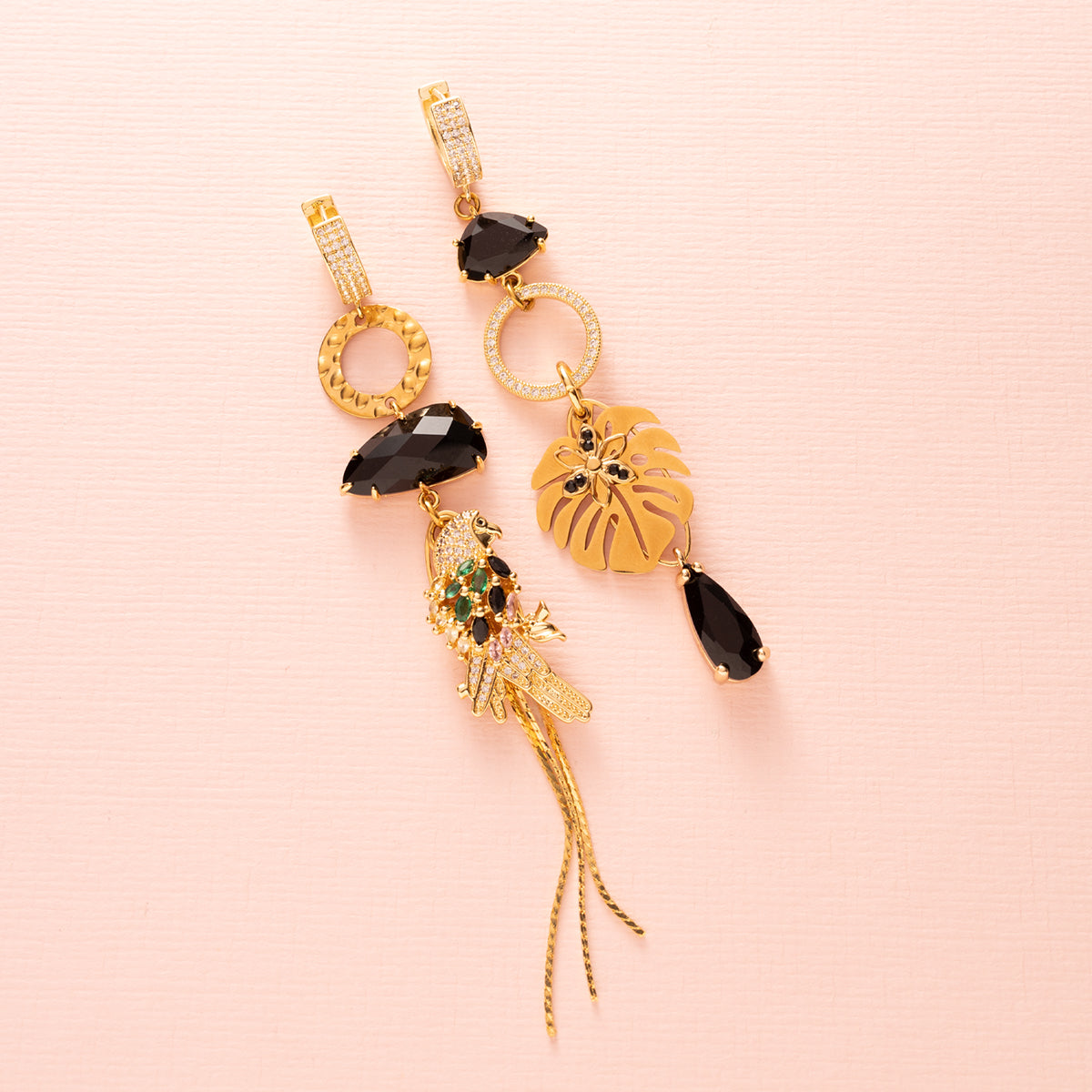 Laat je meevoeren naar de mysterieuze nachtelijke jungle met deze asymmetrische  oorbellen. Aan de ene kant schittert een elegante papegaai met diepzwarte stenen, terwijl de andere kant wordt gesierd door een stijlvol palmblad. Groot, opvallend en speels – perfect voor wie durft te stralen met een uniek design.