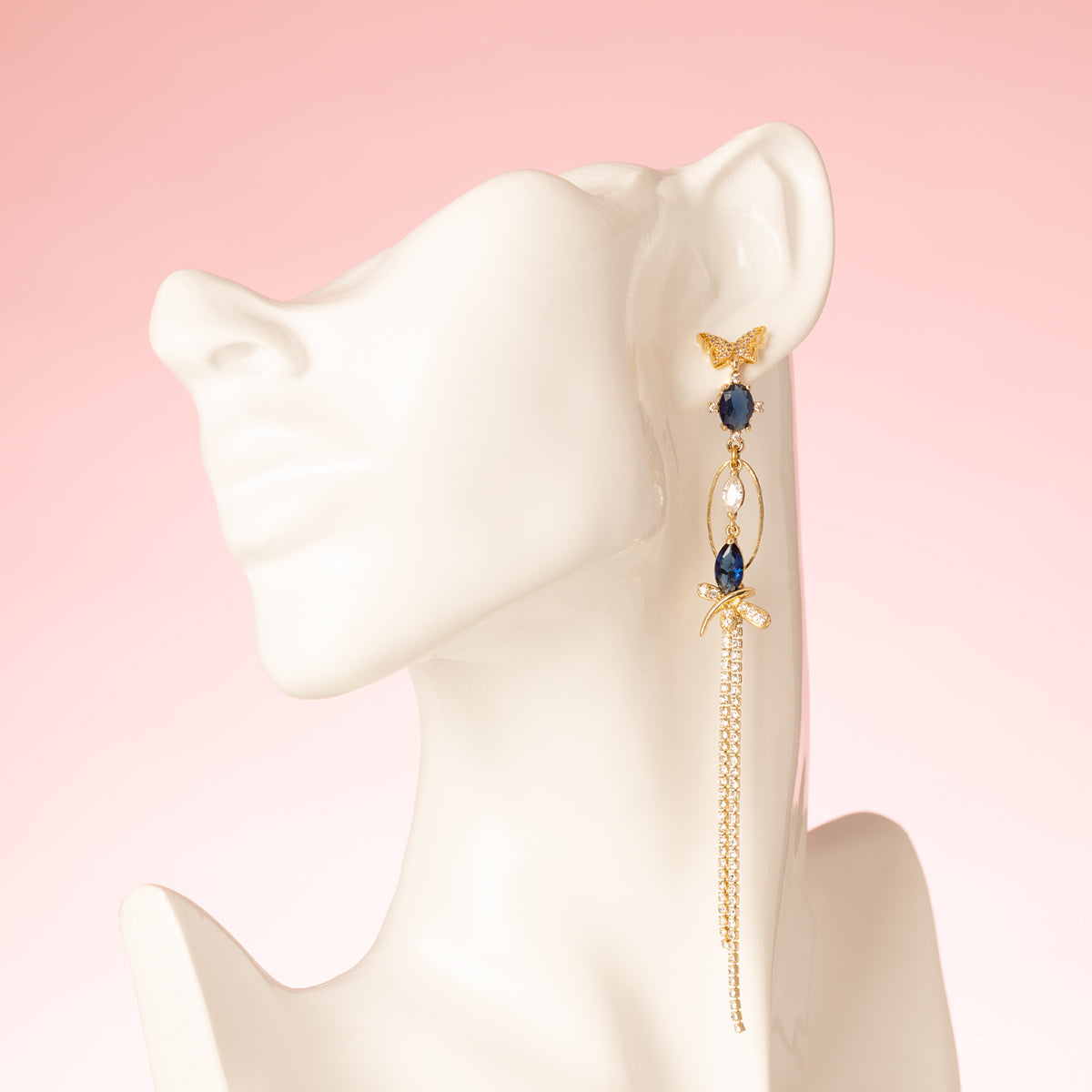 Asymmetrische Statement Oorbellen met zirkonia vlinder oorstekers, aan de linker oorbel een grote zirkonia vlinder met donkerblauw aan de rechter oorbel een kleinere donker blauwe zirkonia vlinder.