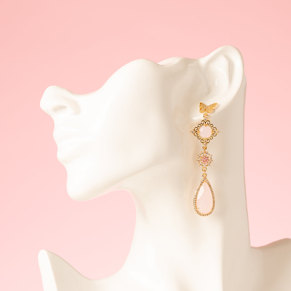 Asymmetrische statement oorbellen met zirkonia vlinder oorstekers. Een mix van glanzende en mat roze stenen en een roze vlinder