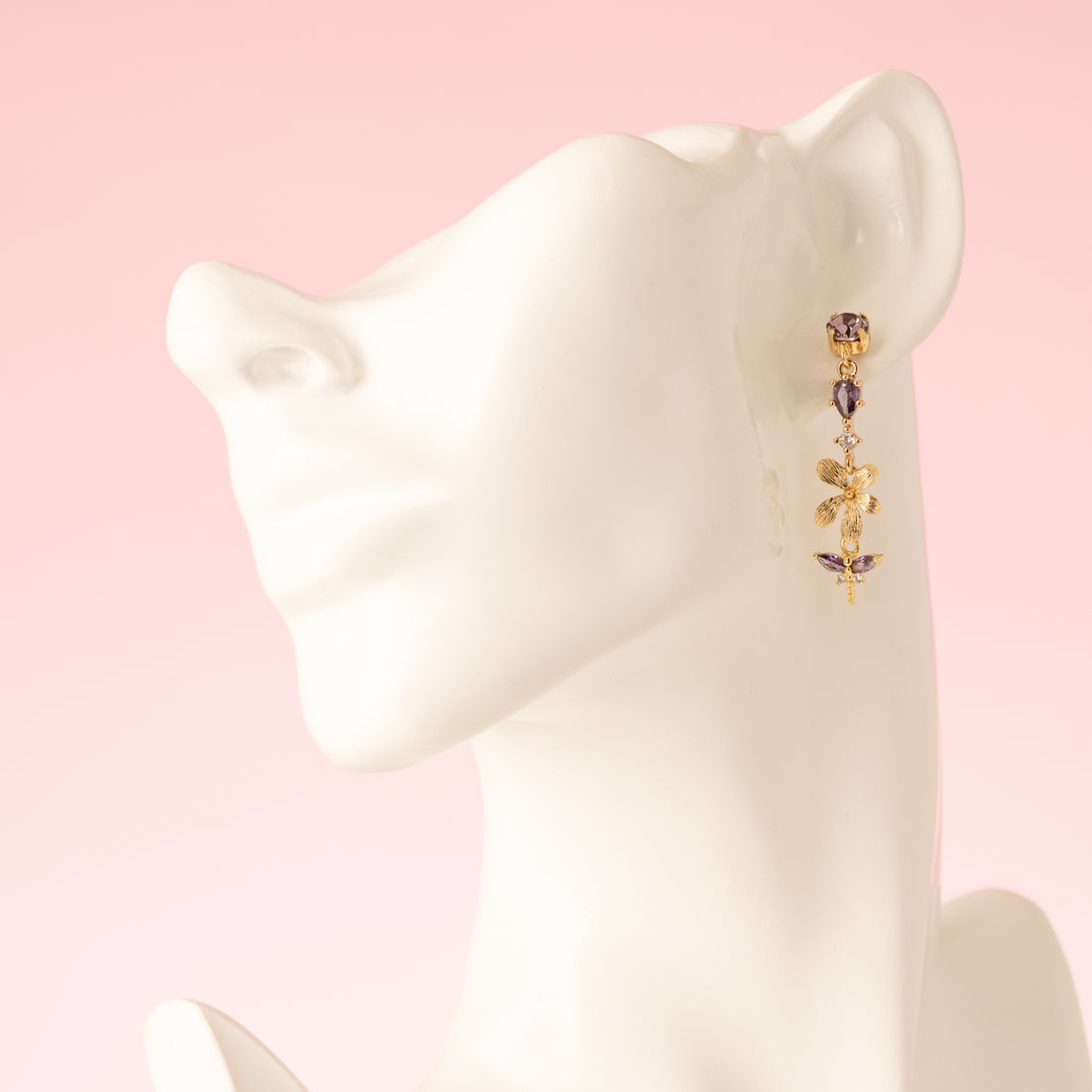 Laat je betoveren door de natuurlijke elegantie van de Lavender Garden asymmetrische oorbellen. De oorbel heeft paarse Swarovski oorstekers, een paars zirkonia tussenstuk en een delicate bloem, waaraan een paarse libelle gracieus hangt. De andere oorbel is voorzien van een gouden blaadje met zirkonia steentjes en een paarse druppel, wat het asymmetrische ontwerp extra speels en verfijnd maakt. Perfect voor een etentje, een feestje of een speciale gelegenheid, en een subtiel statement dat je vrouwelijke en e