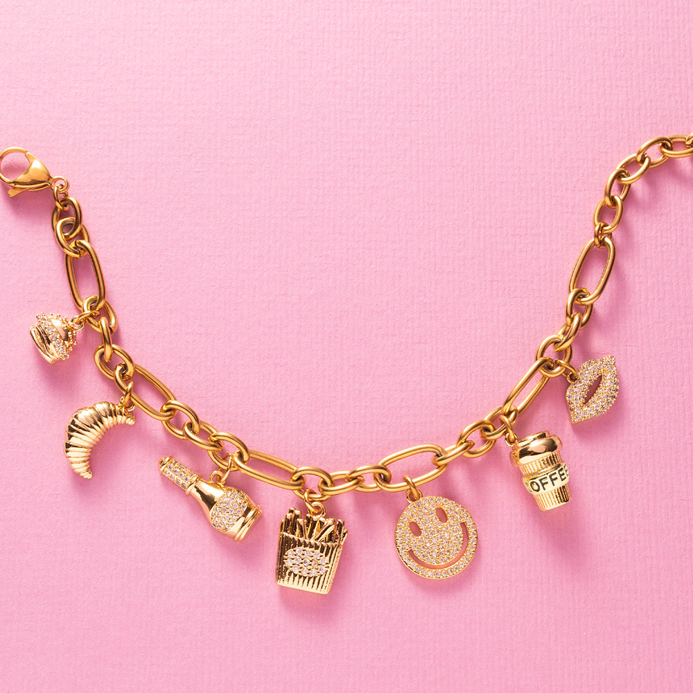 Guilty Pleasure is een eigenzinnige luxe bedelarmband die draait om alles waar je stiekem blij van wordt. Van een croissant bij je koffie, een knapperige frietje, een juicy hamburger tot champagne met een glimlach en een kissable lip. Deze armband viert de kleine verleidingen van het leven.

De gouden afwerking in combinatie met fonkelende zirkonia steentjes geeft elk bedel een elegante sparkle, waardoor fun en luxe naadloos samenkomen. Een echte eyecatcher die luchtig, eigenzinnig en toch stijlvol is.