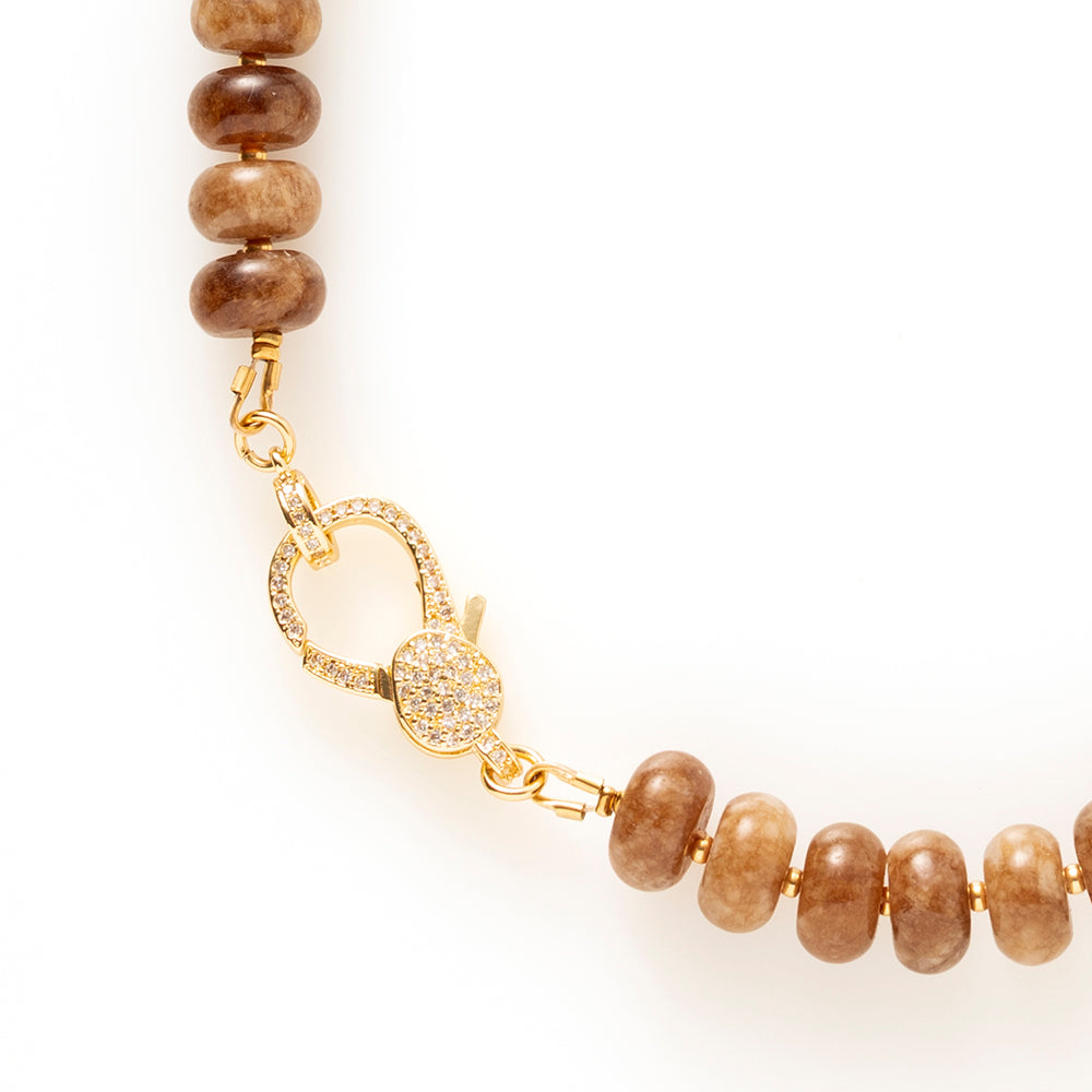 Earth Essence is een elegante natuursteen kralenketting in warme, diepe bruintinten. Deze geeft de ketting een rijke, rustige uitstraling met een verfijnd karakter.

De natuursteen kralen zorgen voor een organische, luxe look. Het opvallende zirkonia slot vormt een stijlvol middelpunt en voegt een subtiele sprankeling toe. Functioneel én decoratief, precies in balans.

Dankzij de warme aardetinten is Earth Essence moeiteloos te combineren met beige, crème, zwart en andere natuurlijke kleuren. Een tijdloos s