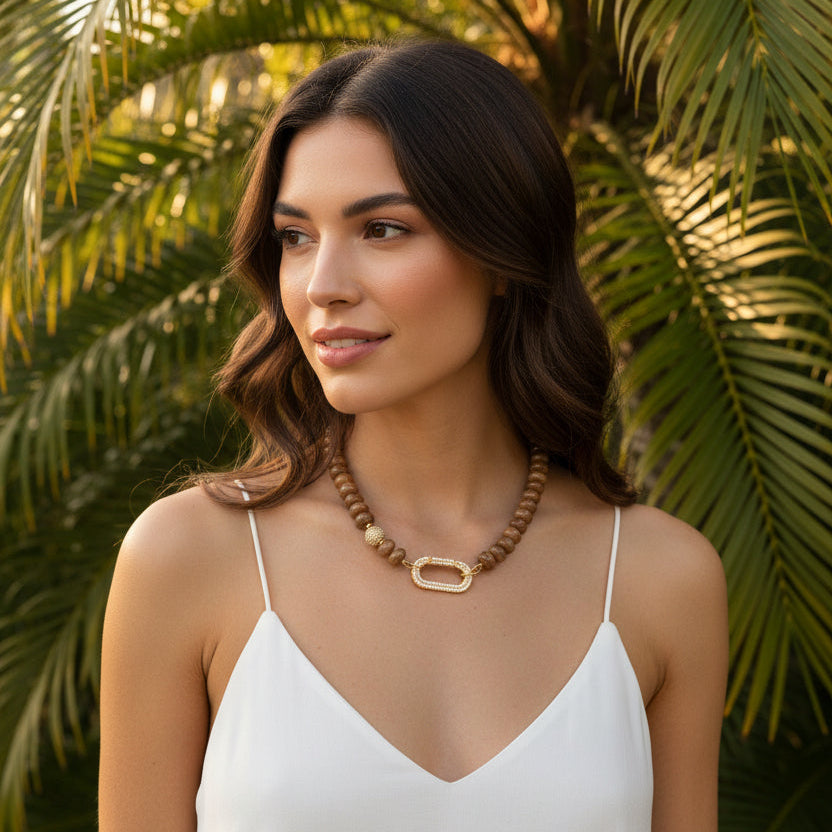 Earth Essence – Signature Clasp is uitgevoerd met dezelfde warme bruine natuursteen kralen. De tint is diep en natuurlijk, waardoor de ketting moeiteloos combineert met zowel lichte als donkere outfits.

Het verschil zit in het zirkonia slot. Deze variant heeft een ander type sluiting (veersluiting) dat een eigen uitstraling geeft: groot, sprankelend en opvallend als designaccent. Het slot fungeert niet alleen als sluiting, maar ook als stijlvol detail dat gezien mag worden.