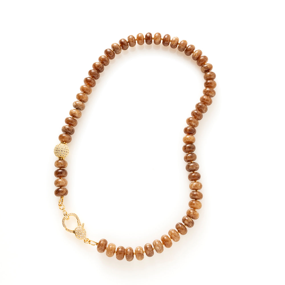Earth Essence is een elegante natuursteen kralenketting in warme, diepe bruintinten. Deze geeft de ketting een rijke, rustige uitstraling met een verfijnd karakter.

De natuursteen kralen zorgen voor een organische, luxe look. Het opvallende zirkonia slot vormt een stijlvol middelpunt en voegt een subtiele sprankeling toe. Functioneel én decoratief, precies in balans.

Dankzij de warme aardetinten is Earth Essence moeiteloos te combineren met beige, crème, zwart en andere natuurlijke kleuren. Een tijdloos s