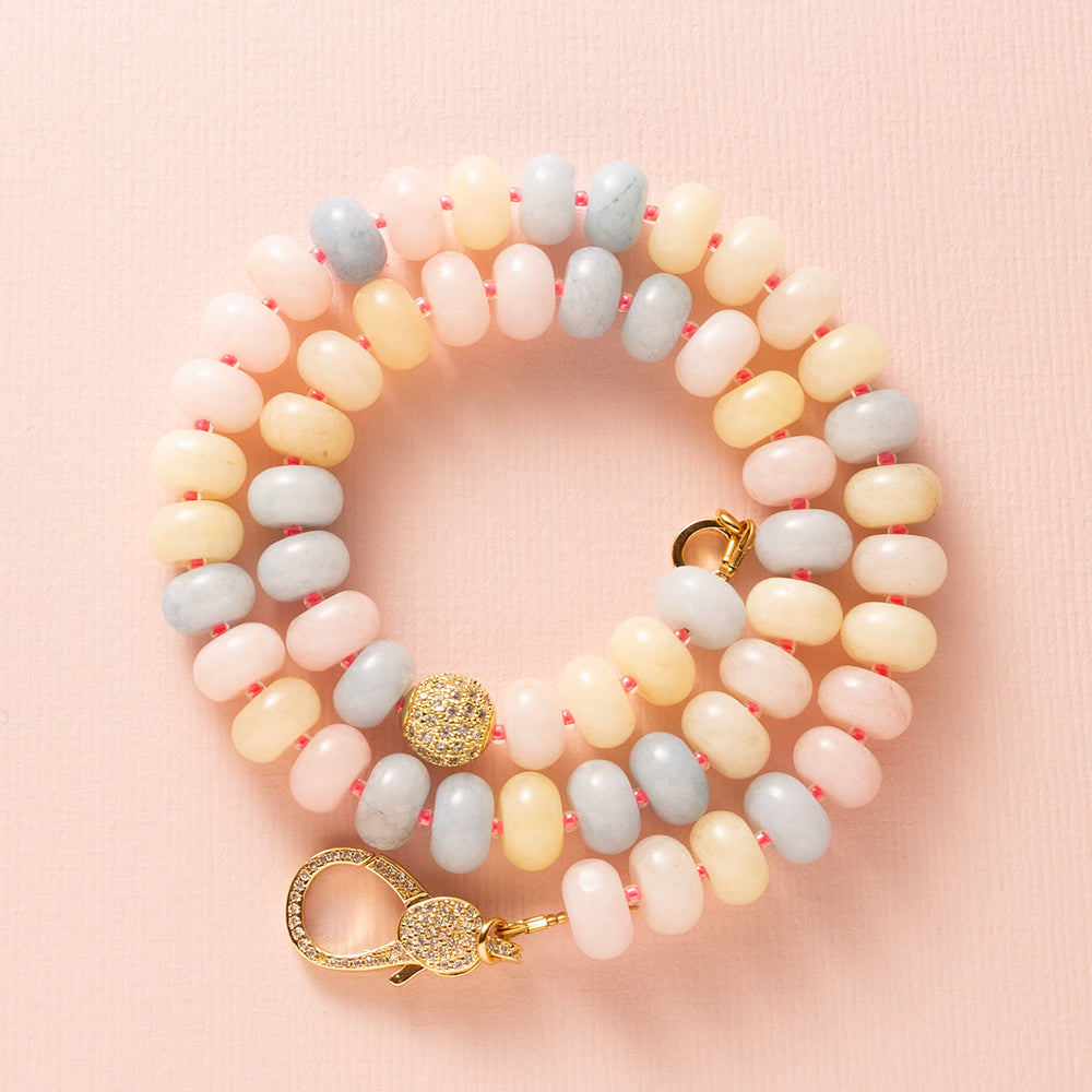 Een speelse knipoog naar de nostalgische snoepjeskettingen, maar dan modern en stijlvol. Deze ketting combineert zachte pasteltinten van Jade met levendige felroze kraaltjes voor een frisse en opvallende uitstraling. Halverwege schittert een zirkonia kraal en aan de voorkant pronkt een groot zirkonia slot, wat deze ketting tot een echte eyecatcher maakt. Perfect voor wie een kleurrijk en elegant statement wil dragen.