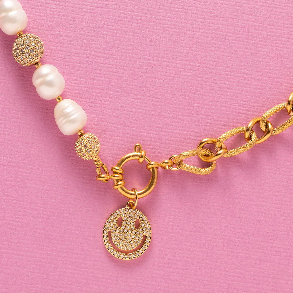 Deze moderne parelketting combineert het beste van twee werelden: de zachte elegantie van zoetwaterparels en de krachtige uitstraling van een opvallende schakel. Aan de voorkant zit een stijlvol boeislot met een zirkonia smiley die je eenvoudig kunt verwijderen. Zo wissel je moeiteloos tussen speels en puur. Een trendy maar tijdloos ontwerp dat zowel stoer als chique gedragen kan worden, passend bij elke stijl en gelegenheid.