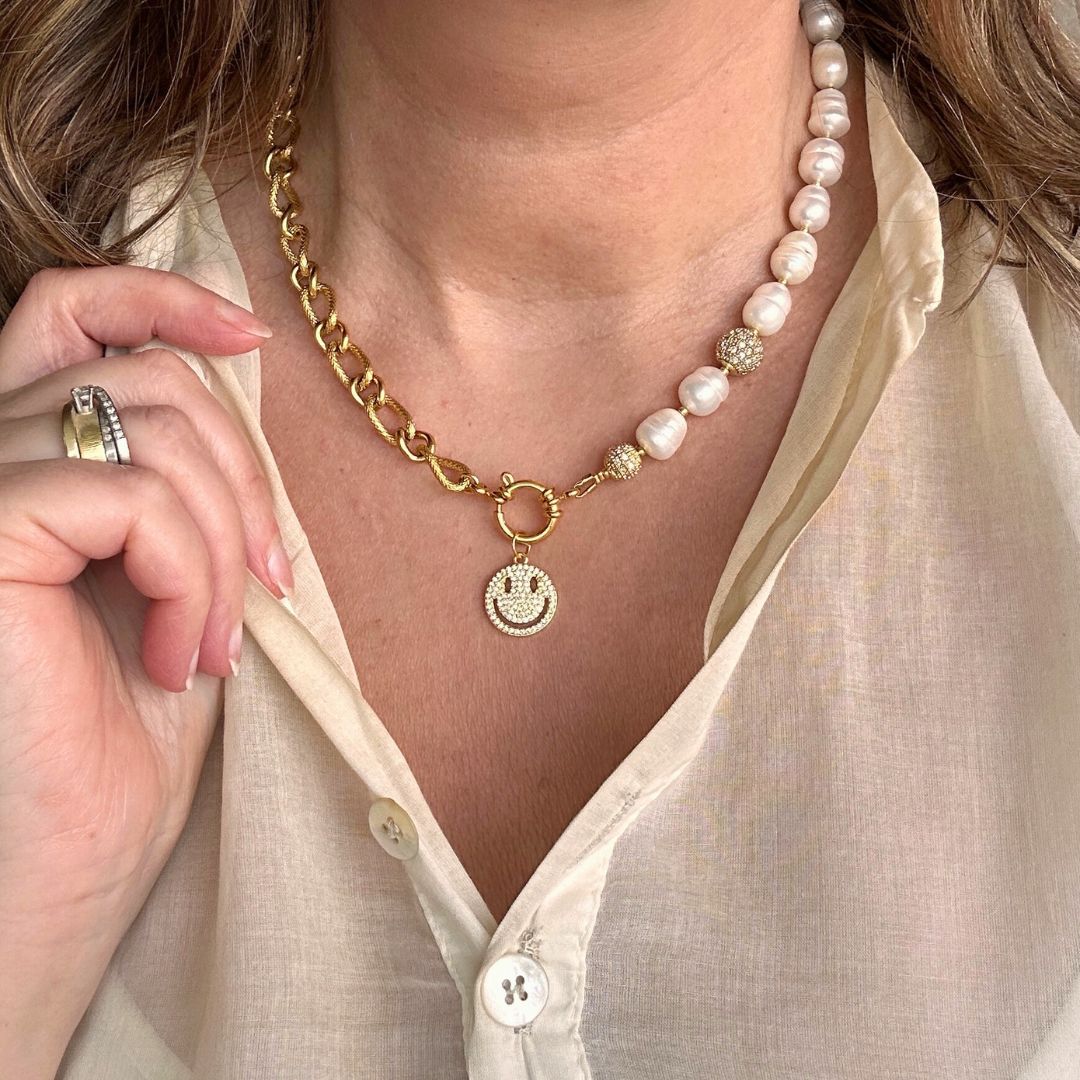 Deze moderne parelketting combineert het beste van twee werelden: de zachte elegantie van zoetwaterparels en de krachtige uitstraling van een opvallende schakel. Aan de voorkant zit een stijlvol boeislot met een zirkonia smiley die je eenvoudig kunt verwijderen. Zo wissel je moeiteloos tussen speels en puur. Een trendy maar tijdloos ontwerp dat zowel stoer als chique gedragen kan worden, passend bij elke stijl en gelegenheid.