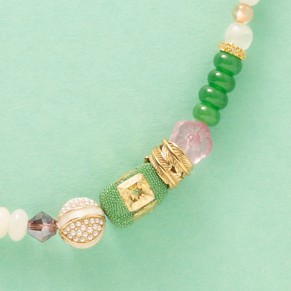 Laat je meevoeren in een dromerige zomerwereld met Wildflower Dreams, een handgemaakte statement ketting in kleurrijke boho-stijl. Deze unieke ketting combineert grote natuursteen kralen, fonkelende zirkonia’s en glaskralen in warme tinten zoals groen, warm oranje, paars, roze en wit. De combinatie van natuurlijke materialen en sprankelende accenten geeft deze ketting een speelse én elegante uitstraling.