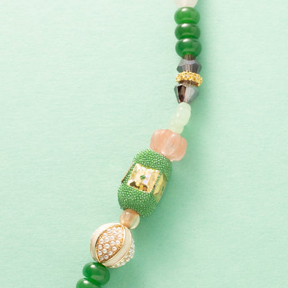 Laat je meevoeren in een dromerige zomerwereld met Wildflower Dreams, een handgemaakte statement ketting in kleurrijke boho-stijl. Deze unieke ketting combineert grote natuursteen kralen, fonkelende zirkonia’s en glaskralen in warme tinten zoals groen, warm oranje, paars, roze en wit. De combinatie van natuurlijke materialen en sprankelende accenten geeft deze ketting een speelse én elegante uitstraling.