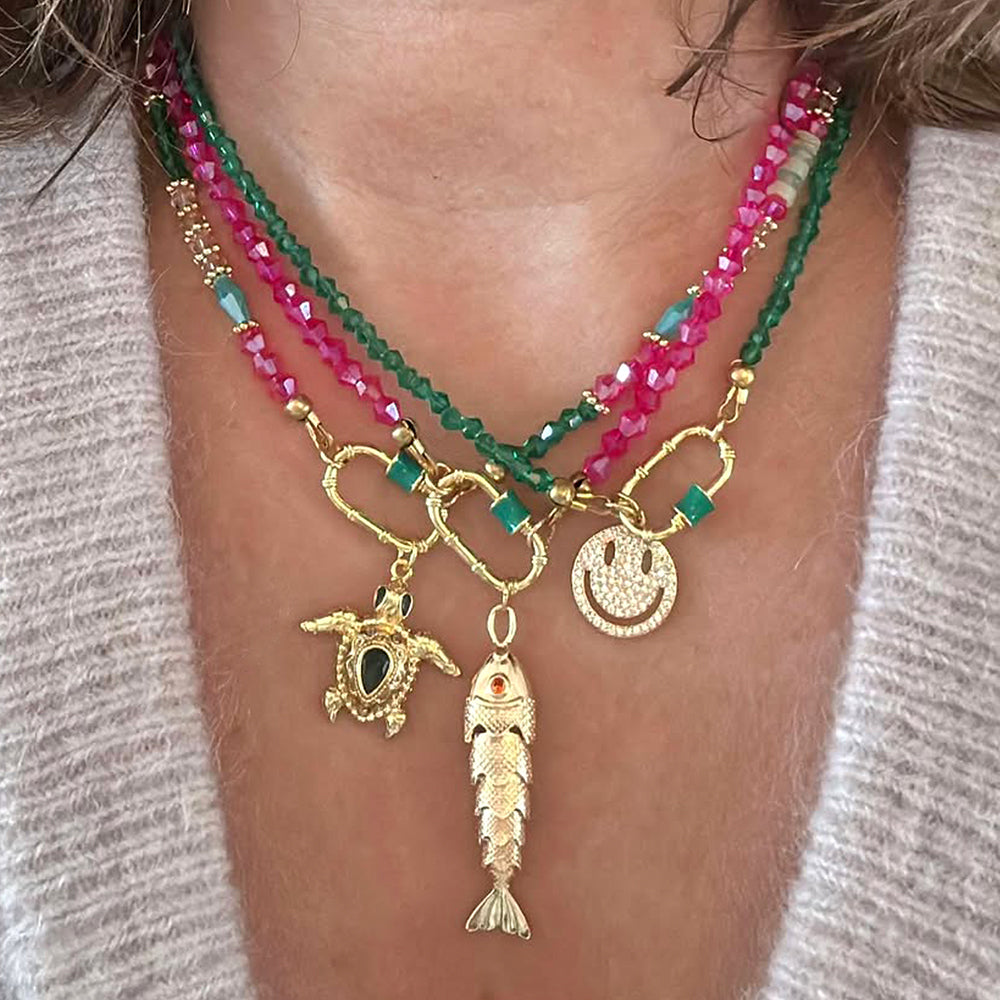 Breng kleur in je look met de Rio beaded necklace! Deze speelse en eigentijdse ketting is gemaakt van sprankelende facetgeslepen glaskralen in levendig magenta, groen of een mix. De opvallende kleuren en het frisse ontwerp maken deze ketting perfect voor zonnige dagen. Deze ketting heeft een opvallend slotje aan de voorzijde welke je open en dicht kan draaien. Hierdoor kun je makkelijk van bedels wisselen. (de ketting is exclusief de bedels, deze kun je apart selecteren.)