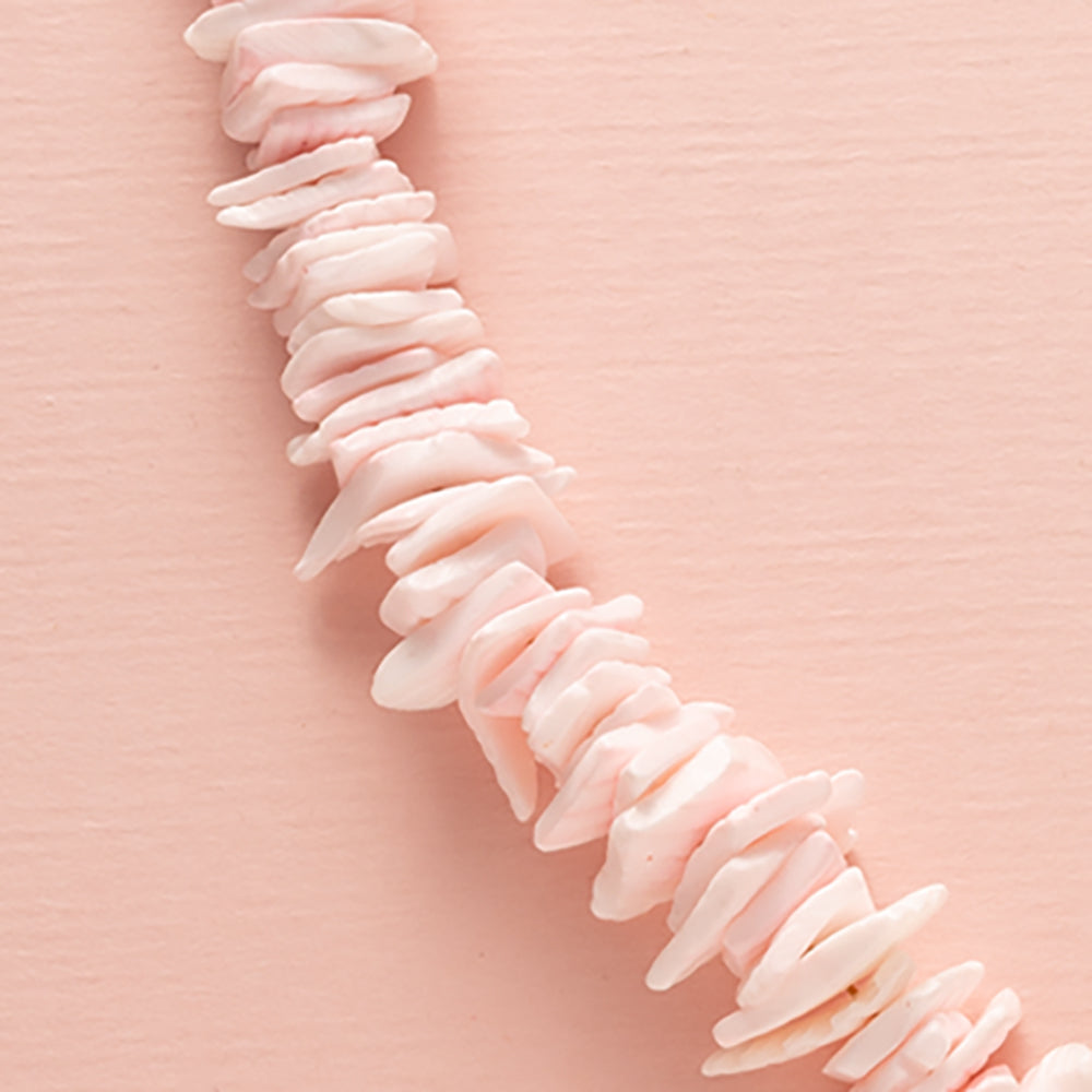 Ontdek de betoverende charme van deze ketting met schelp snippers in licht roze, aangevuld met een schitterende zirkonia kraal en een elegant boeislot aan de voorkant. Deze opvallende ketting bestaat uit twee delen: aan de ene kant delicaat gesneden schelp snippers en aan de andere kant een grove schakelketting, wat samen een trendy en elegante uitstraling creëert.