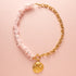 Ontdek de betoverende charme van deze ketting met schelp snippers in licht roze, aangevuld met een schitterende zirkonia kraal en een elegant boeislot aan de voorkant. Deze opvallende ketting bestaat uit twee delen: aan de ene kant delicaat gesneden schelp snippers en aan de andere kant een grove schakelketting, wat samen een trendy en elegante uitstraling creëert.