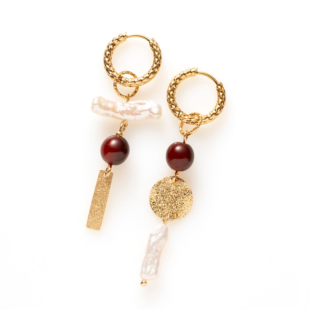Pearl Rebel combineert stoerheid met elegantie. Het gehamerde goud en de getextureerde plaatjes geven de oorbellen lef en de barokke zoetwaterparels maken ze vrouwelijk. De glanzende two-tone resin kralen in bordeaux/bruin voegen een warm kleuraccent toe.

Het warme bordeaux/bruin geeft diepte en het goud vangt het licht. Zoetwaterparels hebben van nature elk een eigen vorm, dus geen twee paren zijn gelijk. Het asymmetrische ontwerp geeft deze oorbellen uitgesproken karakter. 