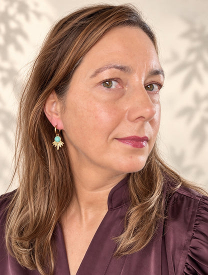 Geef je look een frisse, natuurlijke uitstraling met de Aqua Bloom oorbellen. Aan een fijne gouden klapcreool hangt een bewerkte waaier van gouden blaadjes, gekroond door een ronde amazoniet in zacht blauw. De open vorm vangt het licht en geeft de oorbellen een opvallend silhouet, terwijl het lichte gewicht ze de hele dag comfortabel houdt. Elegant genoeg voor een speciale gelegenheid, maar ook ideaal voor elke dag.