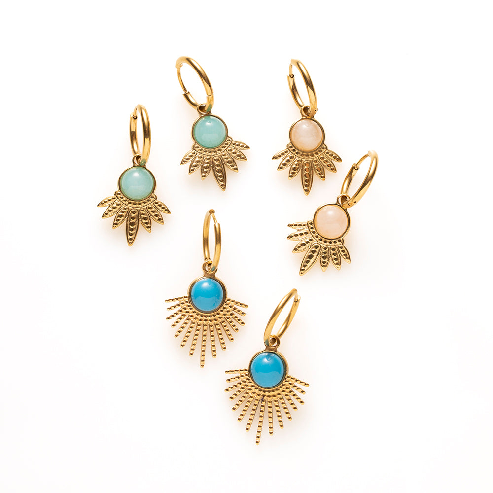Laat je look stralen met de Azure Sun oorbellen. De gouden hanger waaiert uit als een zonnestraal en draagt in het hart een ronde turkoois in helder blauw, een kleur die meteen opvalt tegen het warme goud. De fijne klapcreool houdt het geheel licht en draagbaar, waardoor deze opvallende vorm net zo goed werkt bij een spijkerbroek als bij een zomerse jurk.