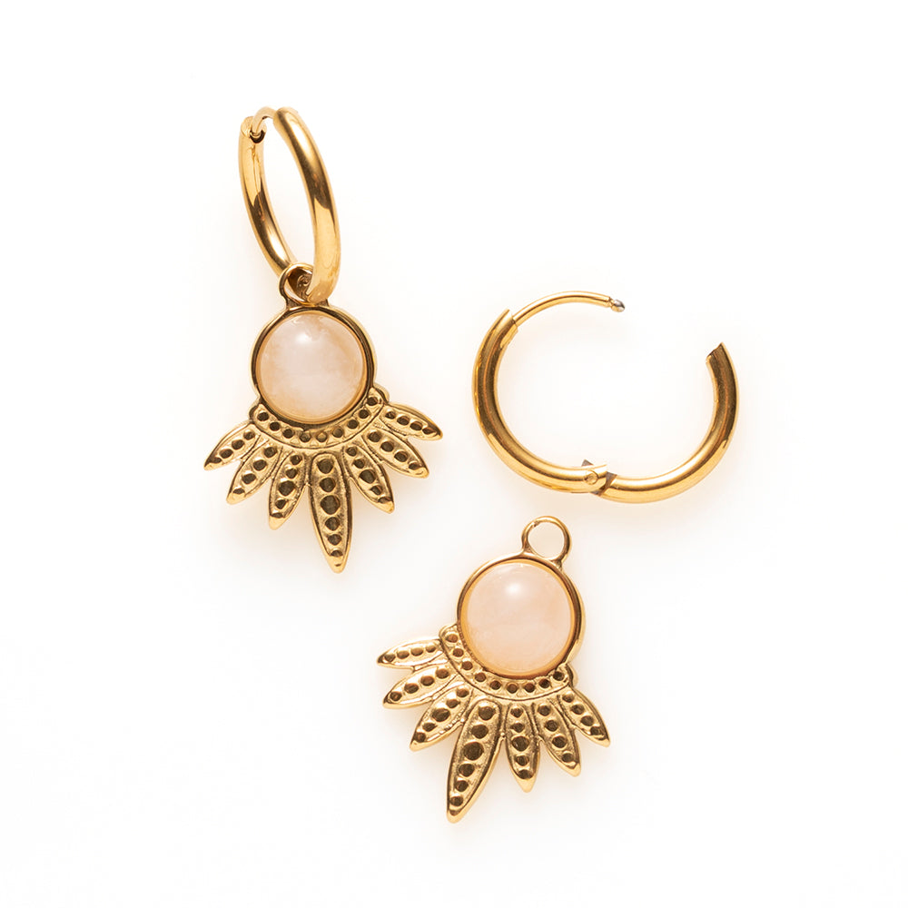 Geef je look een zachte, warme glans met de Rose Dawn oorbellen. Een ronde rozenkwarts in zacht roze rust op een gouden waaier van fijn bewerkte blaadjes, gedragen door een dunne klapcreool. De subtiele kleur van de steen contrasteert mooi met het goud en maakt de oorbellen verfijnd zonder in te boeten aan uitstraling, Tijdloos, perfect voor dagelijks gebruik of een avondje uit.