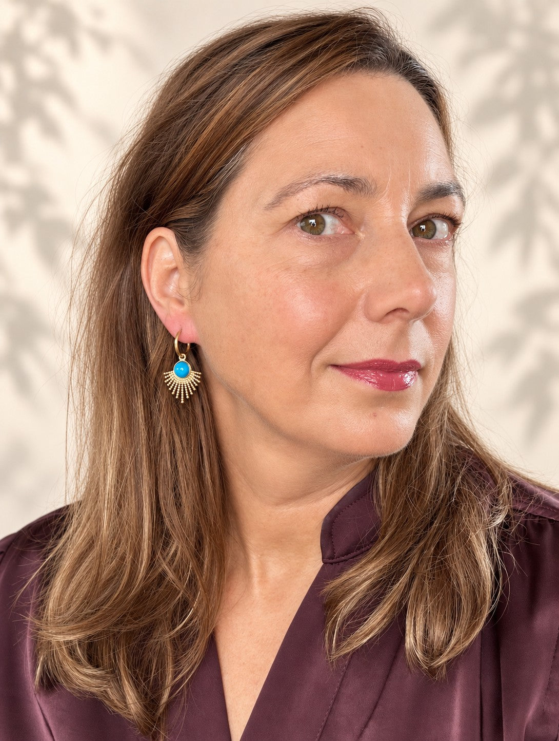 Laat je look stralen met de Azure Sun oorbellen. De gouden hanger waaiert uit als een zonnestraal en draagt in het hart een ronde turkoois in helder blauw, een kleur die meteen opvalt tegen het warme goud. De fijne klapcreool houdt het geheel licht en draagbaar, waardoor deze opvallende vorm net zo goed werkt bij een spijkerbroek als bij een zomerse jurk.