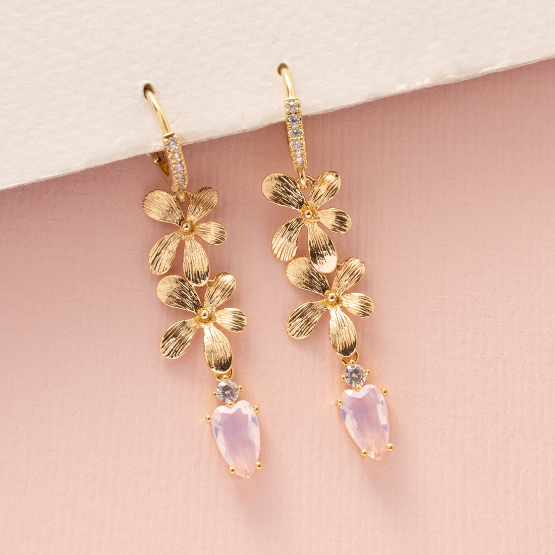 Voeg een subtiel, sprankelend accent toe met de Blushing Bloom oorringen uit de Every Day Glow-collectie. Deze elegante oorringen zijn versierd met twee gouden bloemen en een kleine lichtroze zirkonia druppel die gracieus onderaan hangt. Perfect om je dagelijkse look te verfraaien, naar kantoor of een etentje, en een verfijnd statement te maken dat zowel stijlvol als tijdloos is.