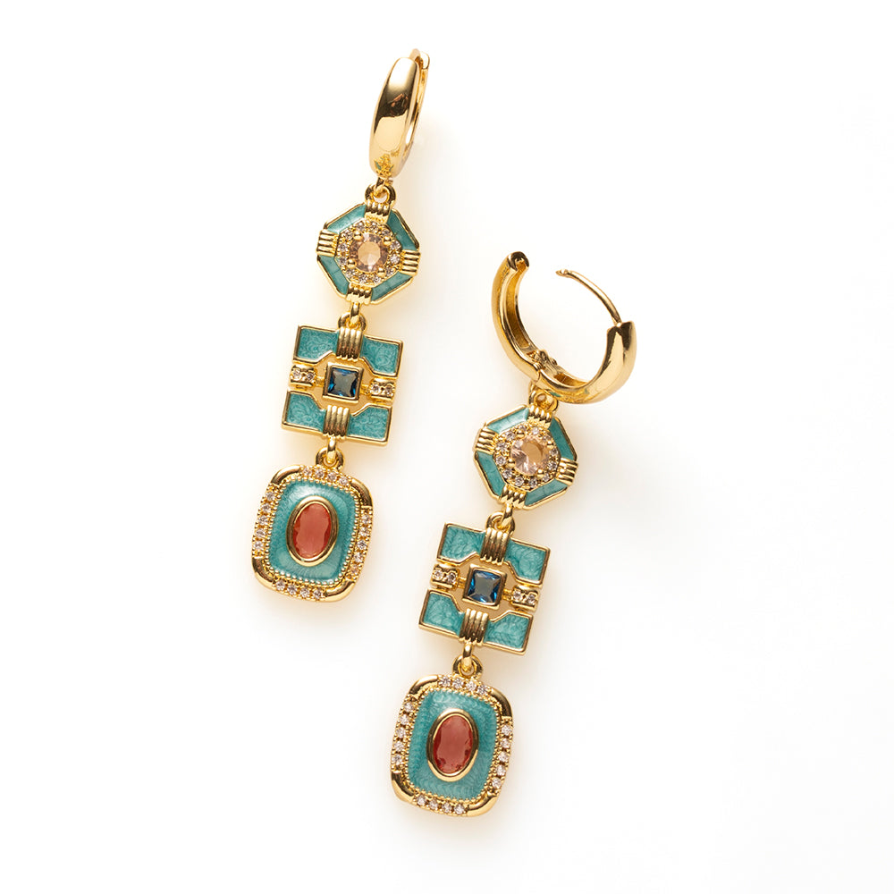 Riviera Deco geeft art deco een eigentijdse twist. Drie geometrische vormen in turquoise emaille hangen sierlijk onder elkaar, elk met een eigen kleuraccent: champagne, diepblauw en roze/rood. Fonkelende zirkonia en warm goud maken het ontwerp rijk en verfijnd, en de lange, verticale lijn geeft het stoerheid.

Deze oorbellen zijn voor de vrouw die iets anders wil dan de standaard gouden oorring: kleur en klasse, zonder dat het te veel wordt. Ze komen het mooist uit bij wit, zwart of denim.
