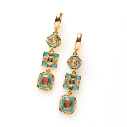 Riviera Deco geeft art deco een eigentijdse twist. Drie geometrische vormen in turquoise emaille hangen sierlijk onder elkaar, elk met een eigen kleuraccent: champagne, diepblauw en roze/rood. Fonkelende zirkonia en warm goud maken het ontwerp rijk en verfijnd, en de lange, verticale lijn geeft het stoerheid.

Deze oorbellen zijn voor de vrouw die iets anders wil dan de standaard gouden oorring: kleur en klasse, zonder dat het te veel wordt. Ze komen het mooist uit bij wit, zwart of denim.