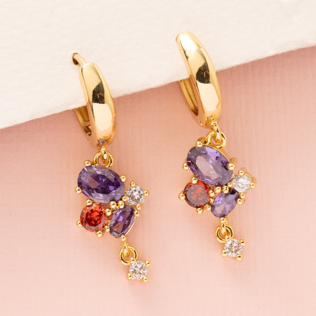 Crimson Glow is klein van formaat maar groots in uitstraling. Deze elegante 18 kt gold plated oorringen zijn afgewerkt met een opvallende bedel vol schitterende zirkonia in paars en rood. Een subtiele eyecatcher voor elke dag of een chique avond uit.