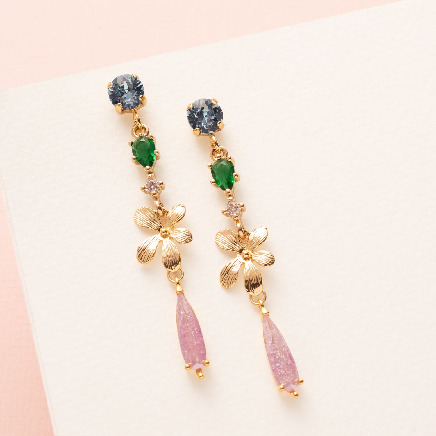Maak een opvallend, verfijnd statement met de Mystic Bloom oorbellen. Fris blauwe Swarovski oorstekers vormen een krachtige basis, gecombineerd met een frisgroen zirkonia tussenstuk onder een gouden bloem. Een lila zirkonia druppel zorgt voor een subtiele sprankeling en elegantie. Perfect om je outfit naar een hoger niveau te tillen, zowel naar kantoor als tijdens een etentje.