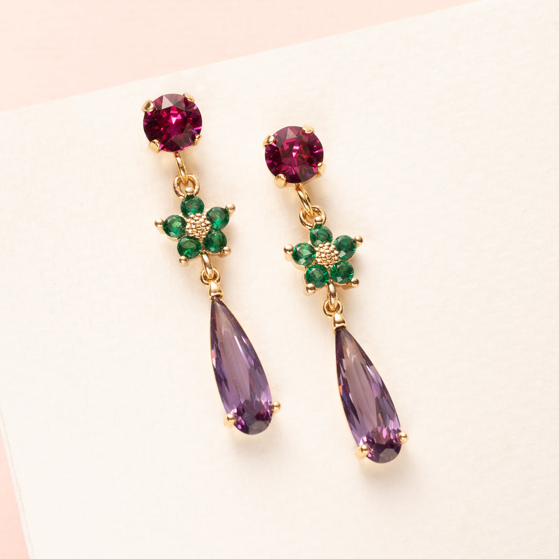 Laat je betoveren door de kleurrijke elegantie van Purple Meadow. Deze fijne statement oorbellen combineren een fuchsia Swarovski oorsteker met een frisgroen kristallen bloemetje en een subtiele paarse druppel van kristalglas. Het resultaat? Een opvallende, maar verfijnde look die je zowel overdag als ’s avonds laat stralen. Perfect voor het najaar, maar tijdloos genoeg om het hele jaar door te dragen. Draag ze naar kantoor of maak je outfit af voor een avondje uit