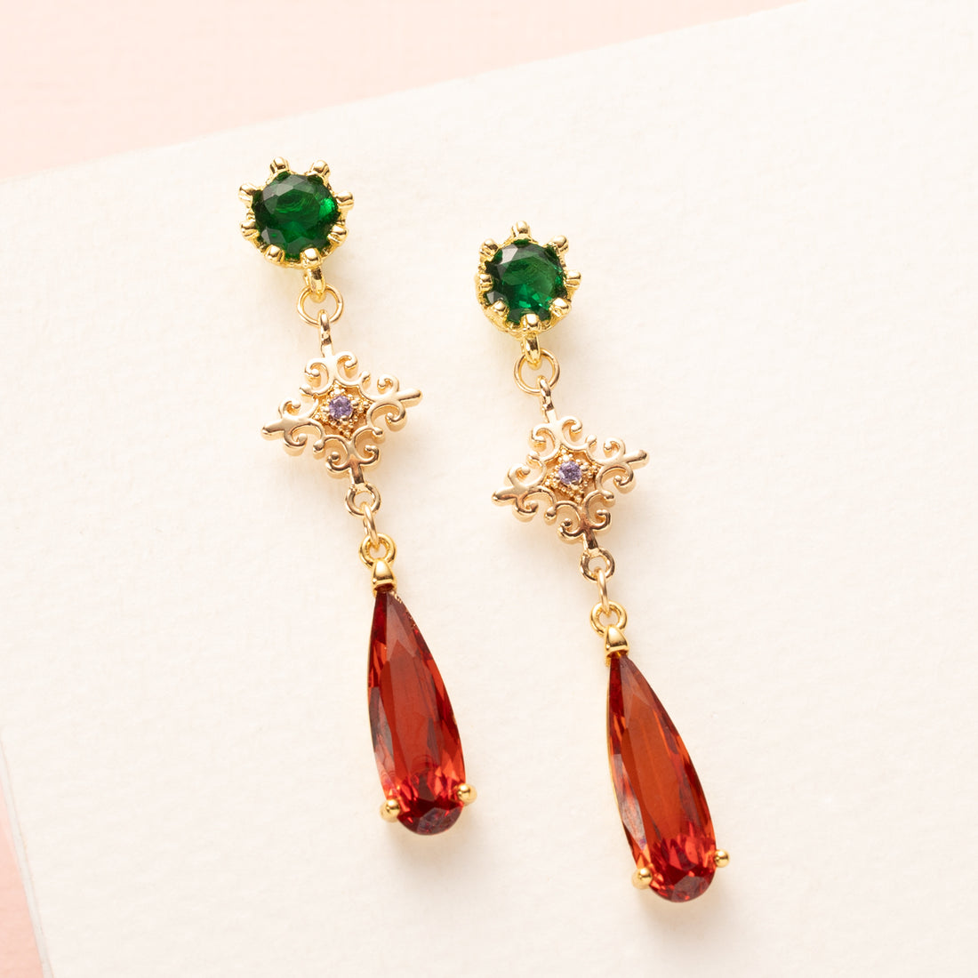 Subtiel en elegant: Autumn Glow – Diamond combineert een groene zirkonia oorsteker met een ruitvormig paars tussenstuk en een opvallende oranje crystal druppel. Fijn, stijlvol en perfect voor een verfijnde herfstlook.