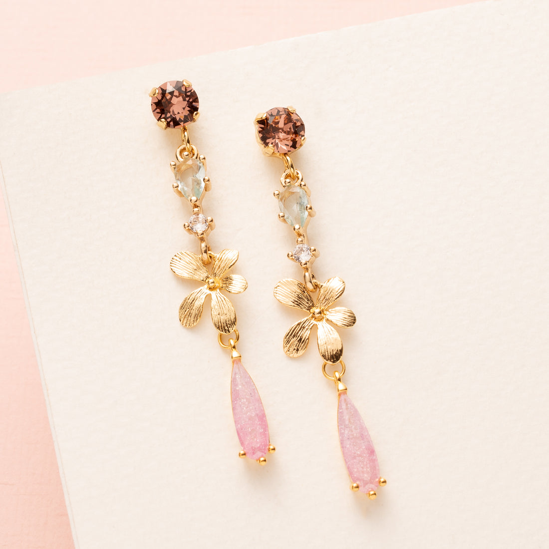 Voeg een vleugje zachte elegantie toe aan je look met de Whispering Rose oorbellen. Deze verfijnde oorbellen hebben een subtiele, pastelroze tint en een sierlijke, iets langere vorm die perfect valt bij iedere outfit. De delicate bloemdetails maken ze tijdloos en vrouwelijk, terwijl ze dankzij hun elegante design zowel naar kantoor als een etentje gedragen kunnen worden. Een subtiel statement dat je persoonlijkheid laat stralen.