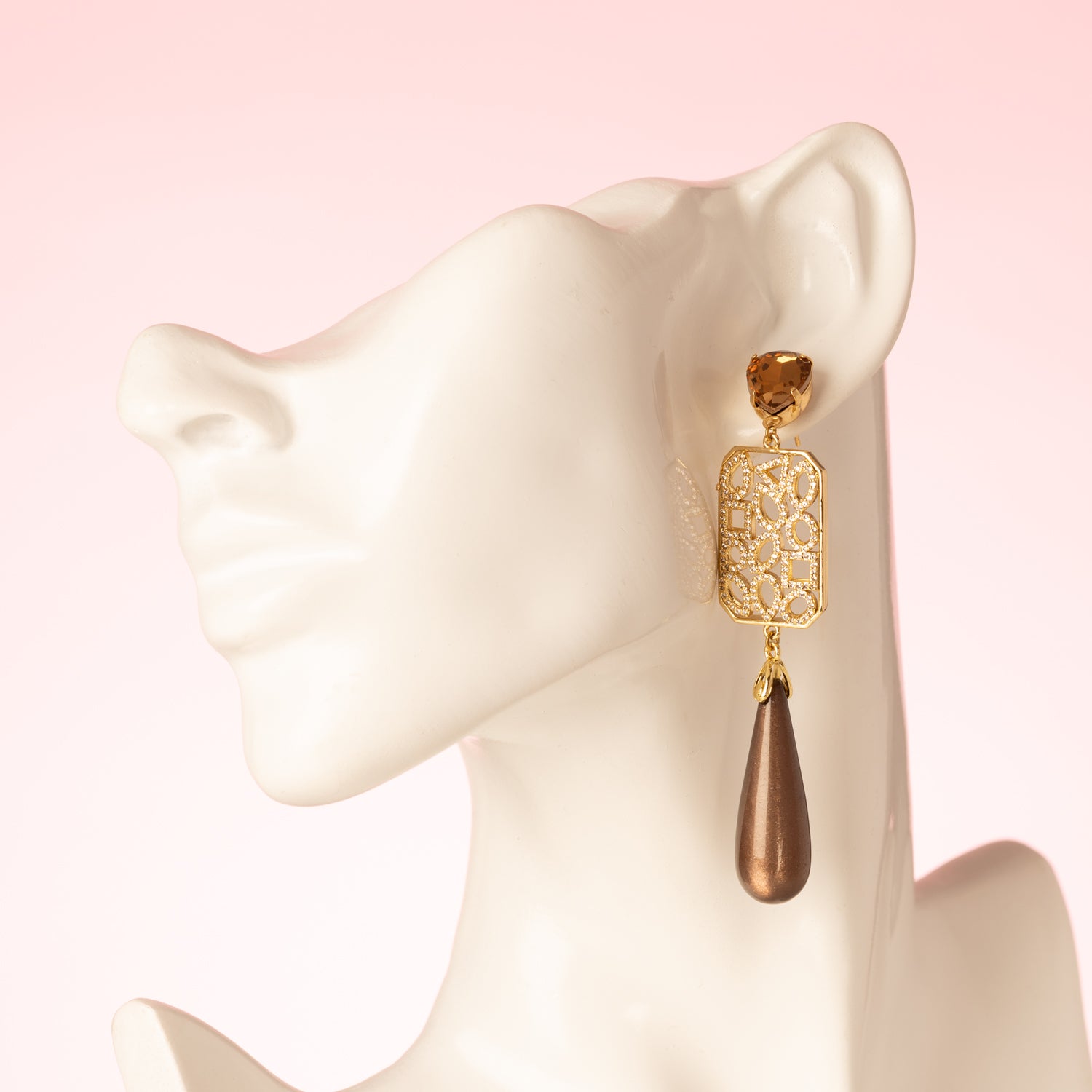 Grand Allure is een spectaculaire statement oorbel die luxe, elegantie en de bruine trendkleur perfect combineert. Kies zelf je stijl met een&amp;nbsp;ronde Swarovski oorsteker of druppelvormige Strass oorsteker in Light Smoked Topaz. Het grote, rechte tussenstuk is versierd met verschillende vormen zirkonia steentjes, en daaronder hangt een glanzende donkerbruine Polaris druppel.

Een oorbel die kracht, glamour en impact uitstraalt – een echte eyecatcher voor vrouwen die durven op te vallen.