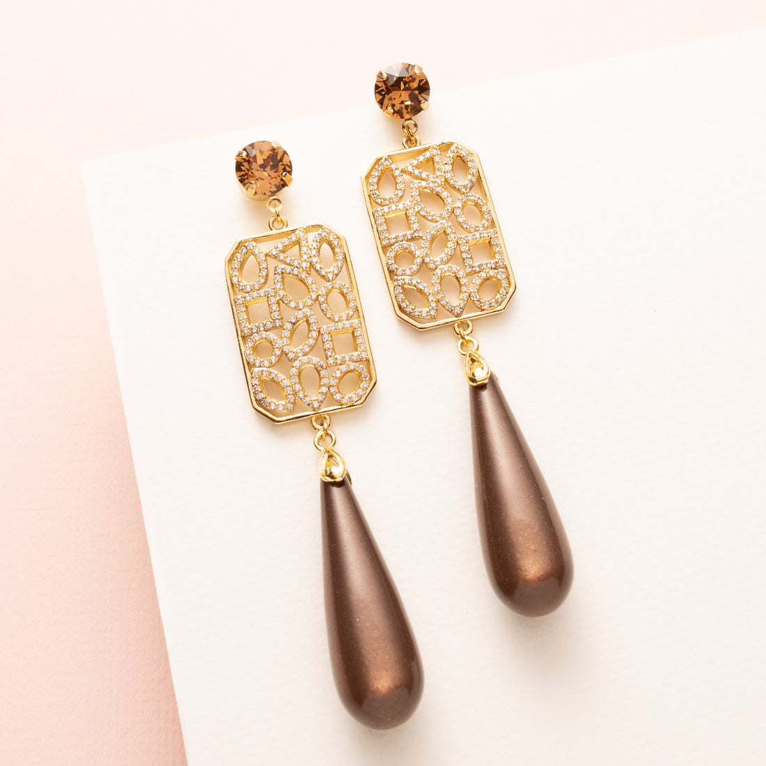 Grand Allure is een spectaculaire statement oorbel die luxe, elegantie en de bruine trendkleur perfect combineert. Kies zelf je stijl met een&amp;nbsp;ronde Swarovski oorsteker of druppelvormige Strass oorsteker in Light Smoked Topaz. Het grote, rechte tussenstuk is versierd met verschillende vormen zirkonia steentjes, en daaronder hangt een glanzende donkerbruine Polaris druppel.

Een oorbel die kracht, glamour en impact uitstraalt – een echte eyecatcher voor vrouwen die durven op te vallen.